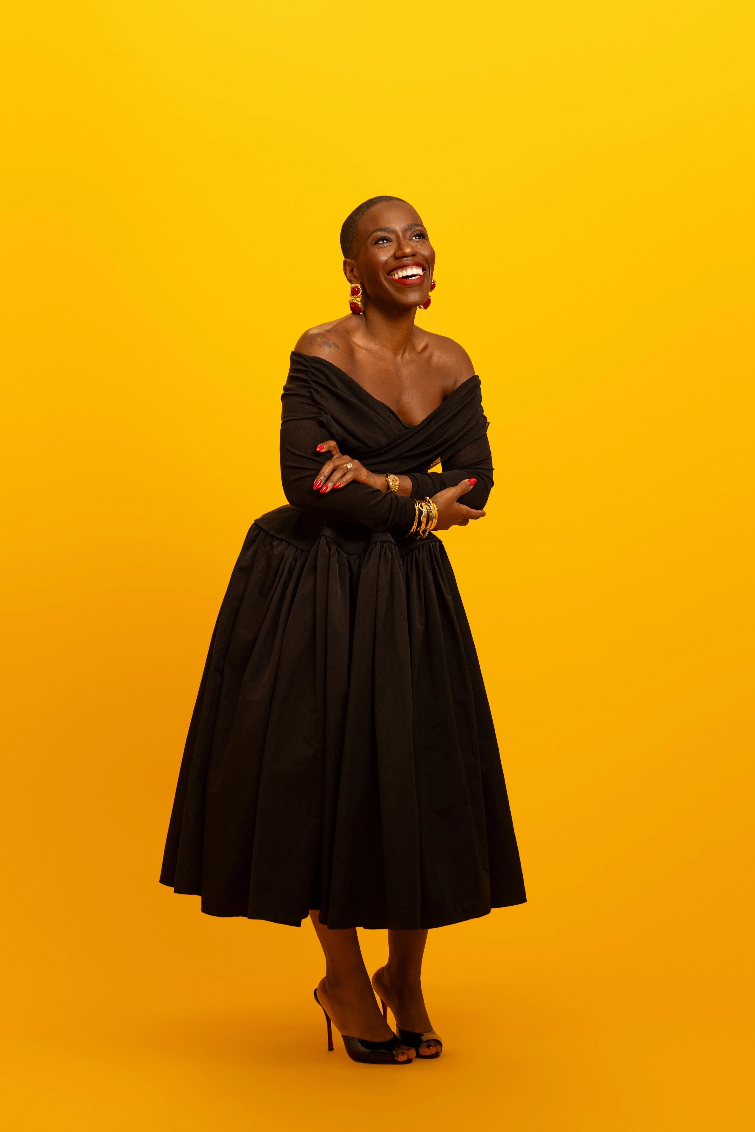 Candice Brathwaite posing dressed in all black on yellow background