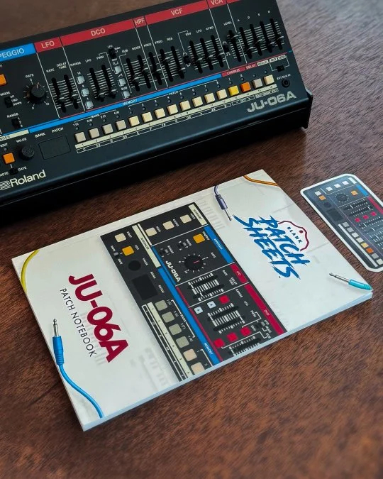 Photo of the Roland JU-06a boutique synthesizer with the Blank Patch Sheets JU-06a notebook and sticker.