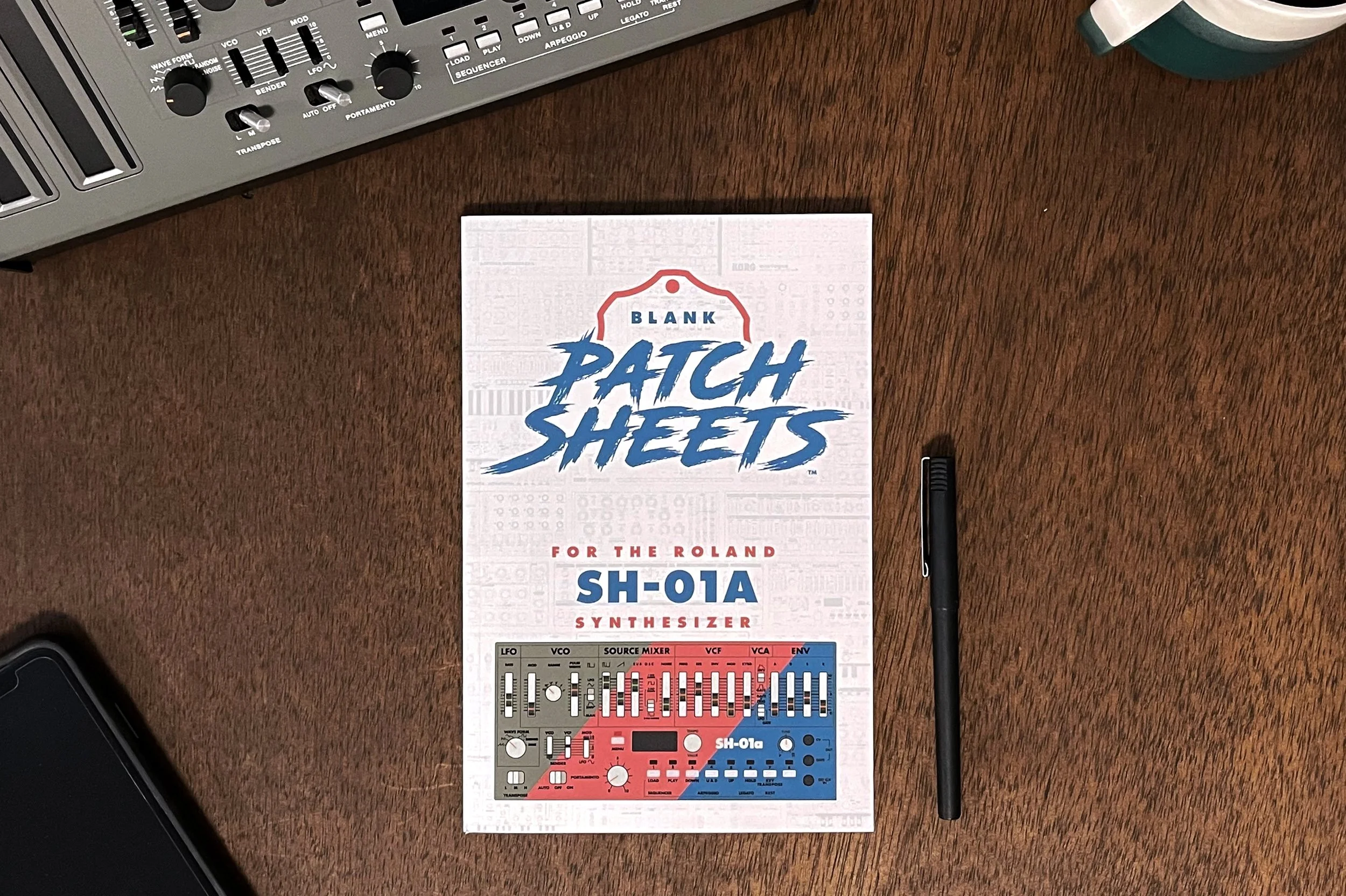 Blank Patch Sheets notebook for the Roland SH-01a shown with the synthesizer near by, a cup of coffee and an iPhone.