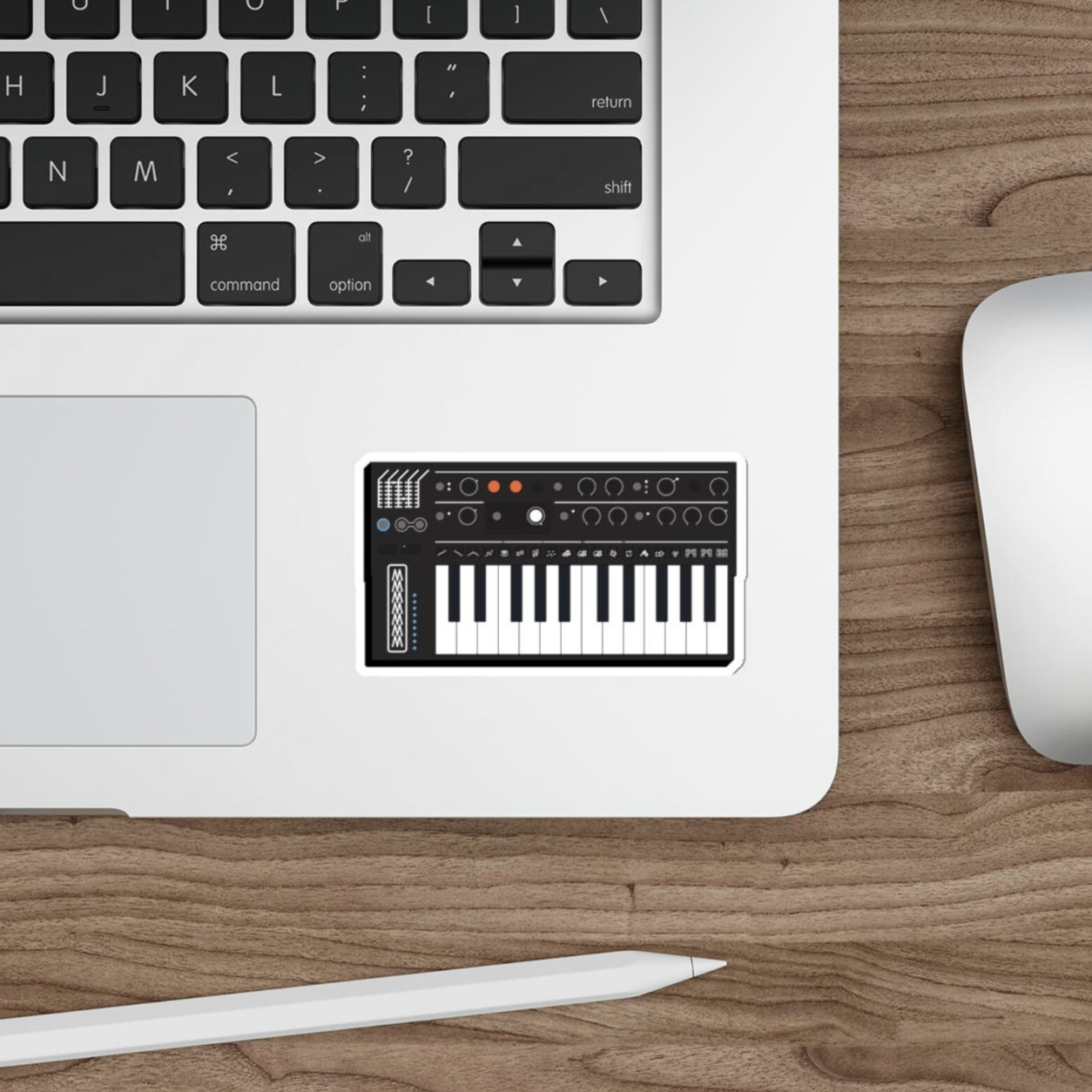 Arturia Minifreak sticker on a macbook pro next to the track pad on a wood table