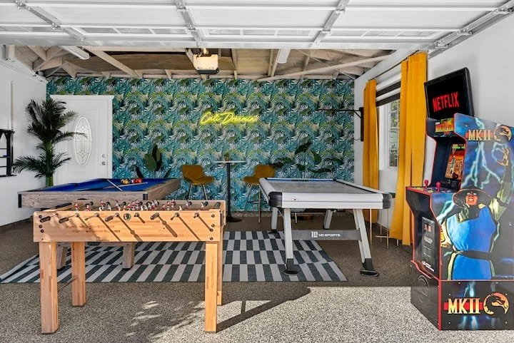 Game room with foosball table, ping-pong table, billiards table, arcade machines, tropical wallpaper, and neon sign