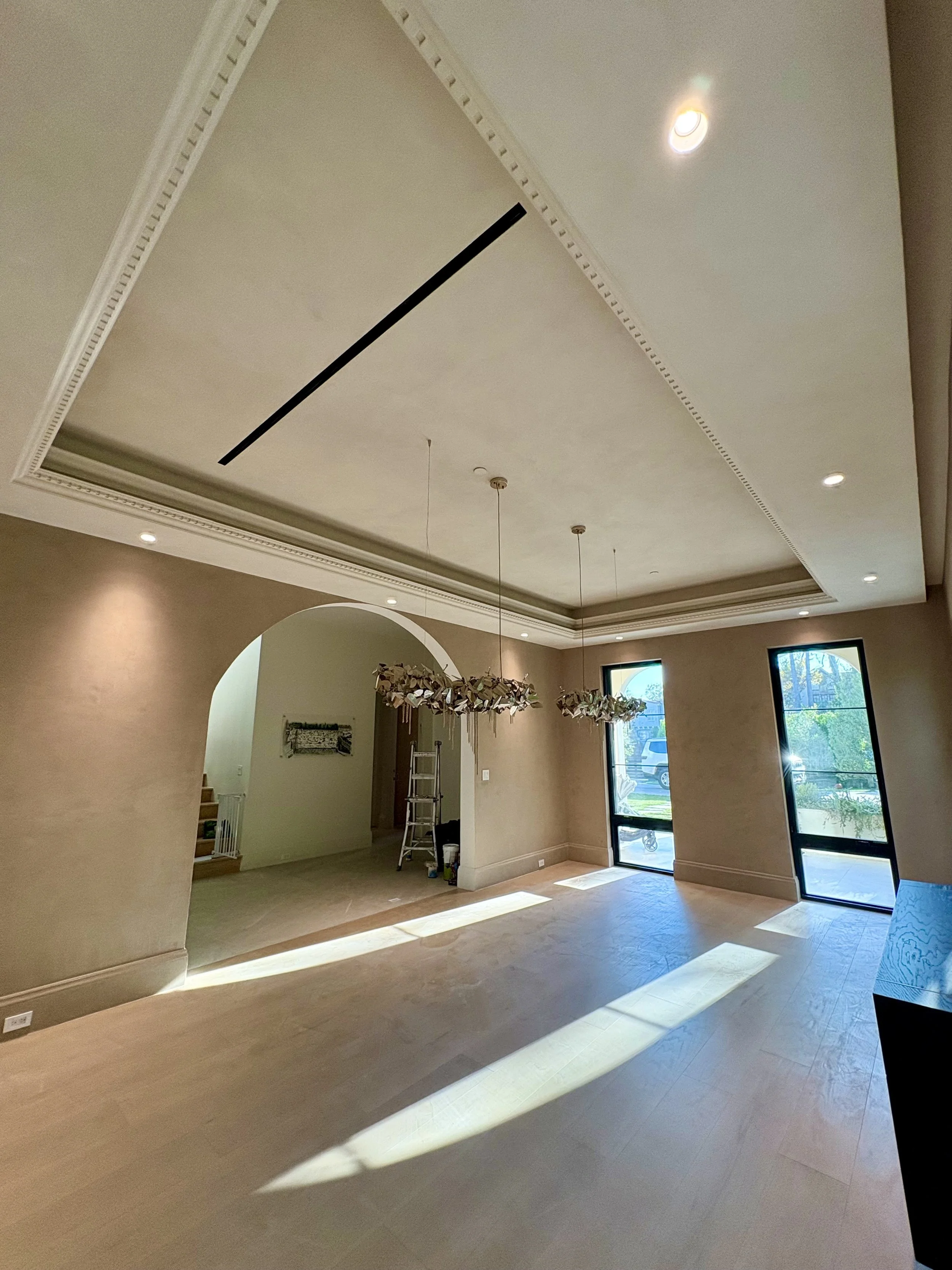 Warm taupe dining room with textured walls, decorative ceiling molding, and an arched doorway.
