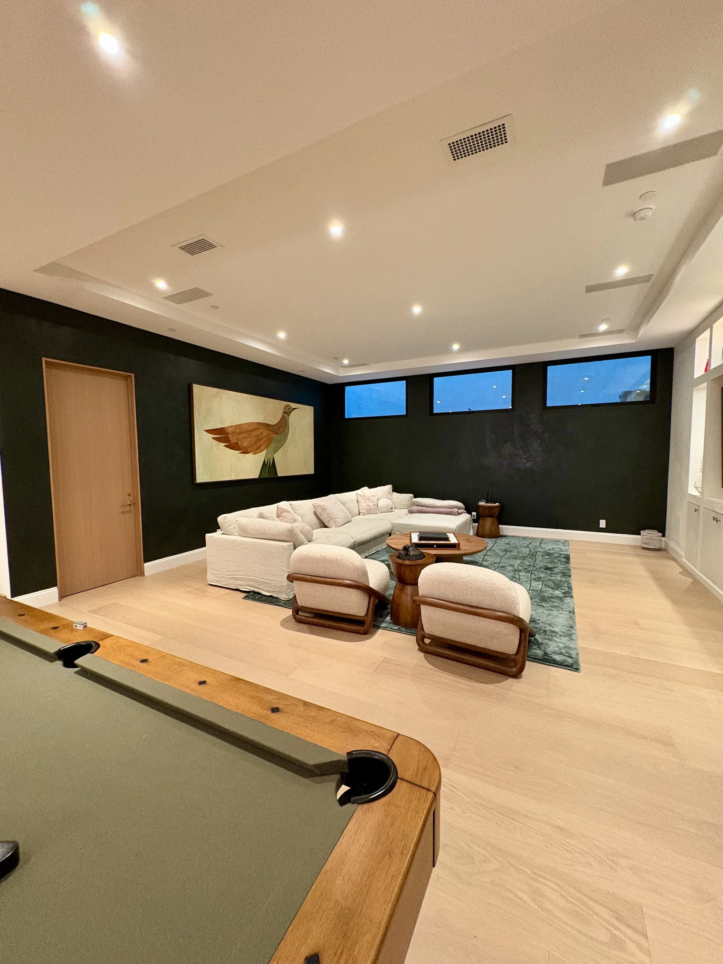 Dark green textured feature wall with natural wood door and framed artwork in a contemporary living space.