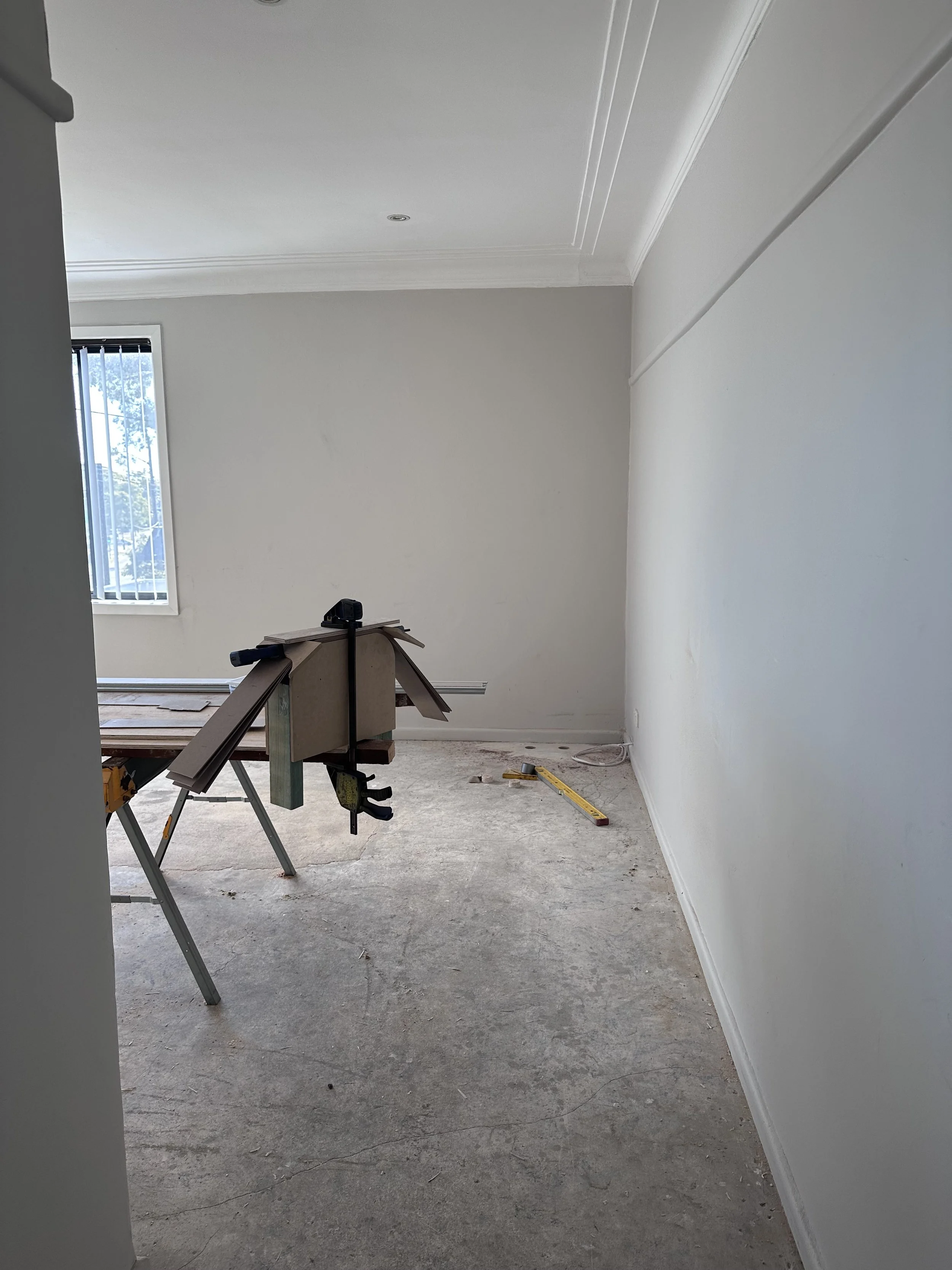 An interior room under construction with a window, some construction tools, and a partially finished floor.