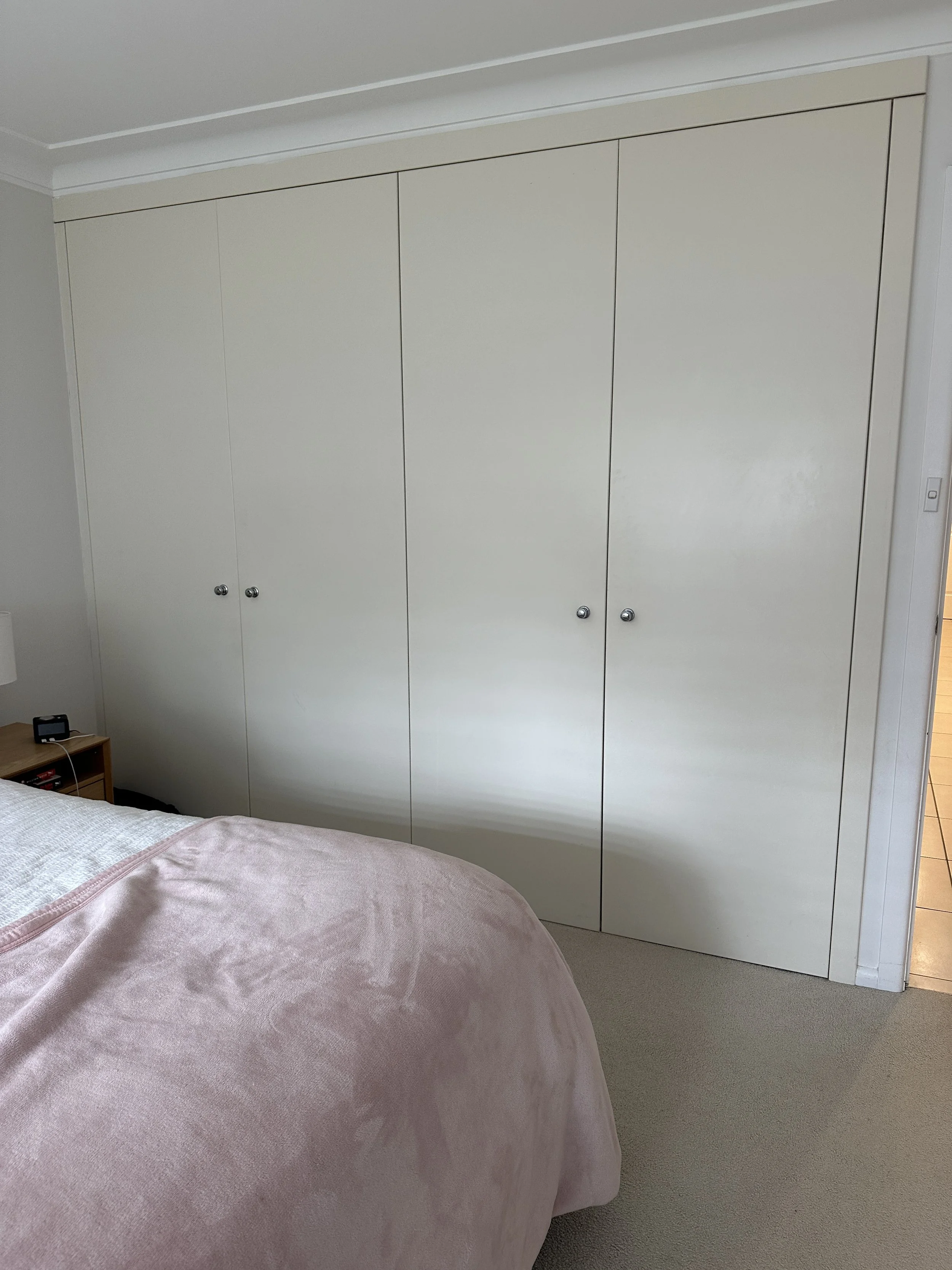 Bedroom with a large white closet and a bed with a pink blanket