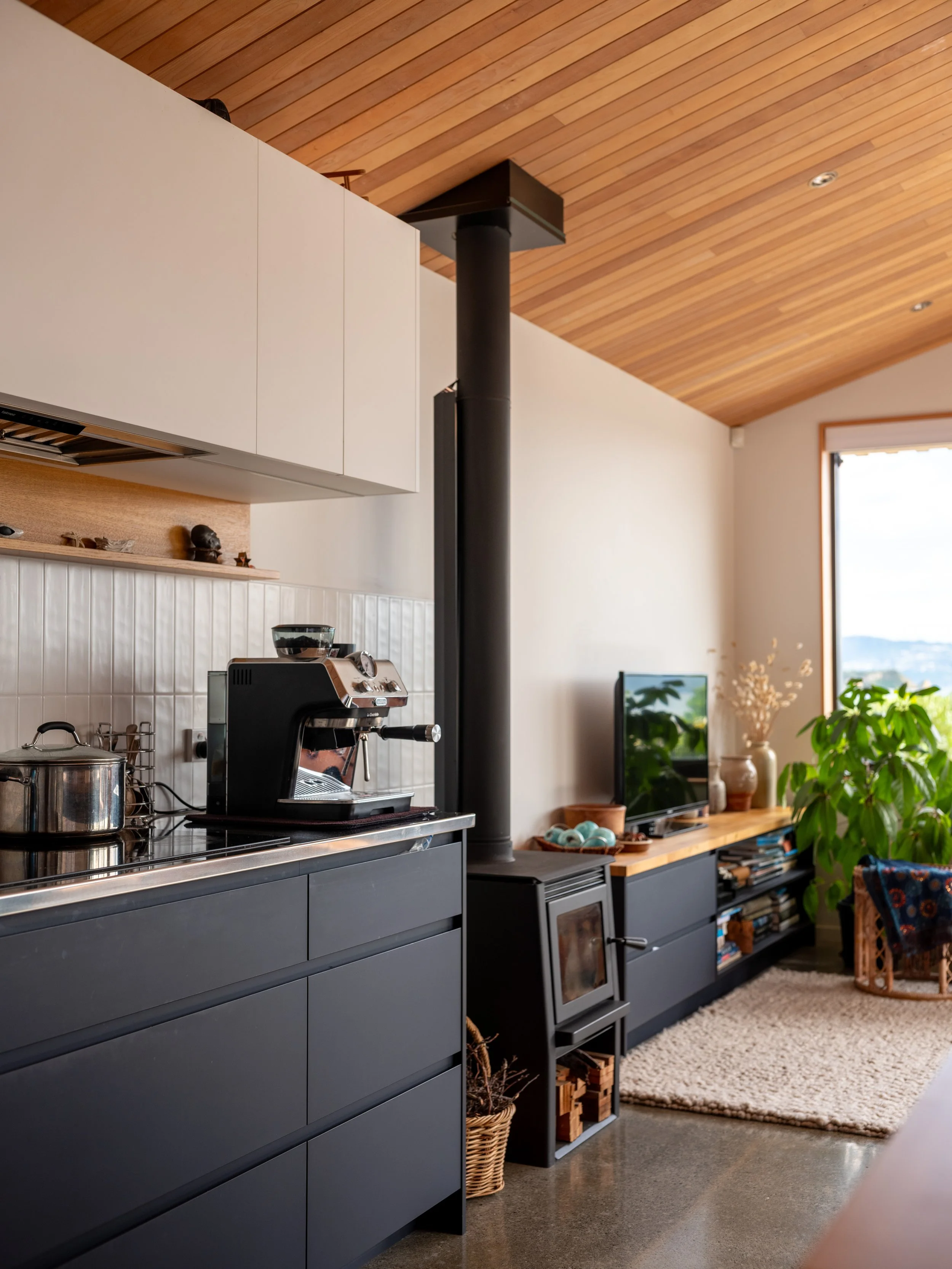Kitchen and living area at Eastbourne House with dark cabinetry, timber detailing and a wood-burning stove.