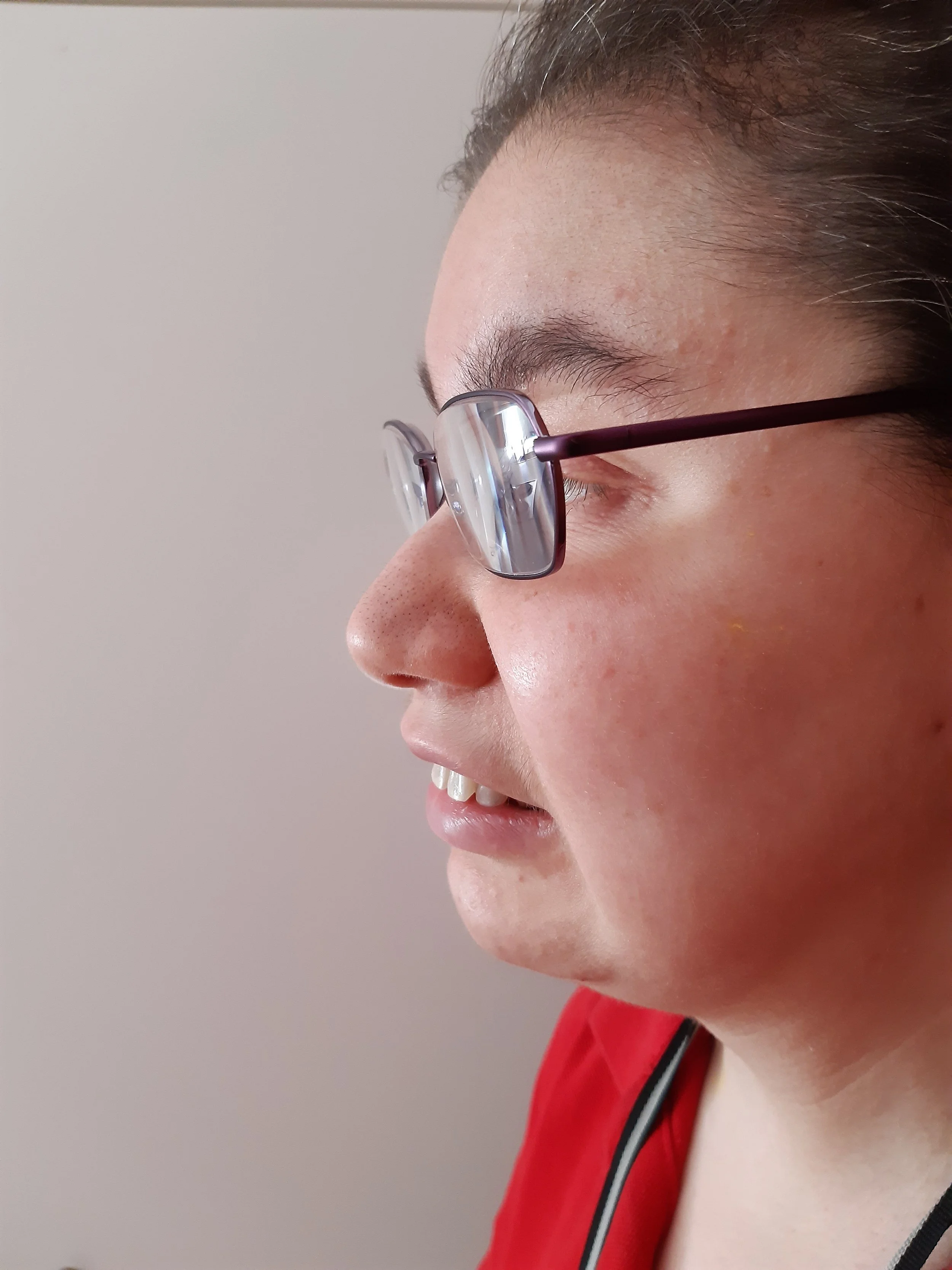 Elina Lie ist im Profil zu sehen. In ihrer Brille reflektiert das Licht und man kann nur erahnen, wohin sie blickt.