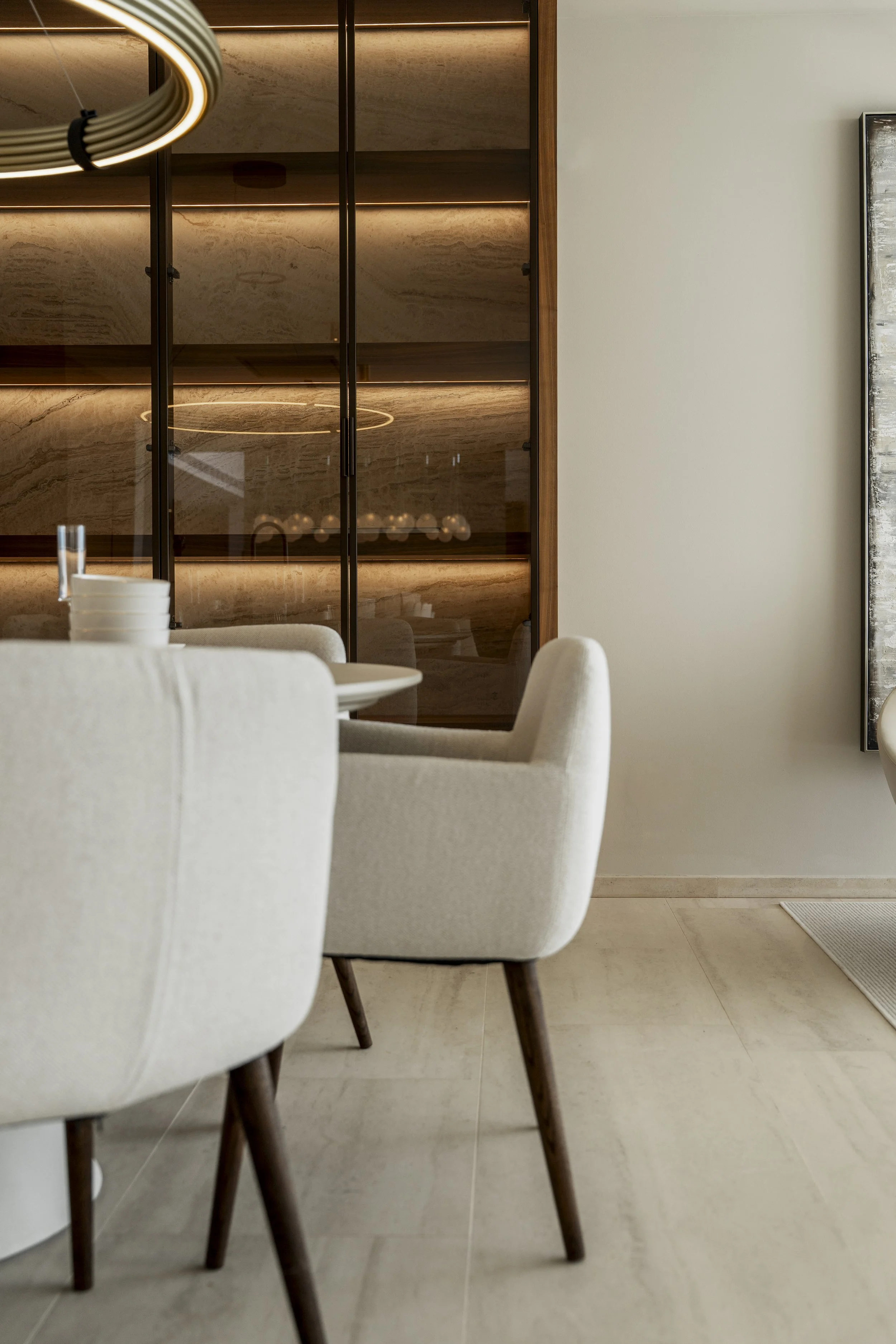 Sala moderna con sofá blanco, cojines decorativos, pared de madera con luces verticales y mesa con libros.