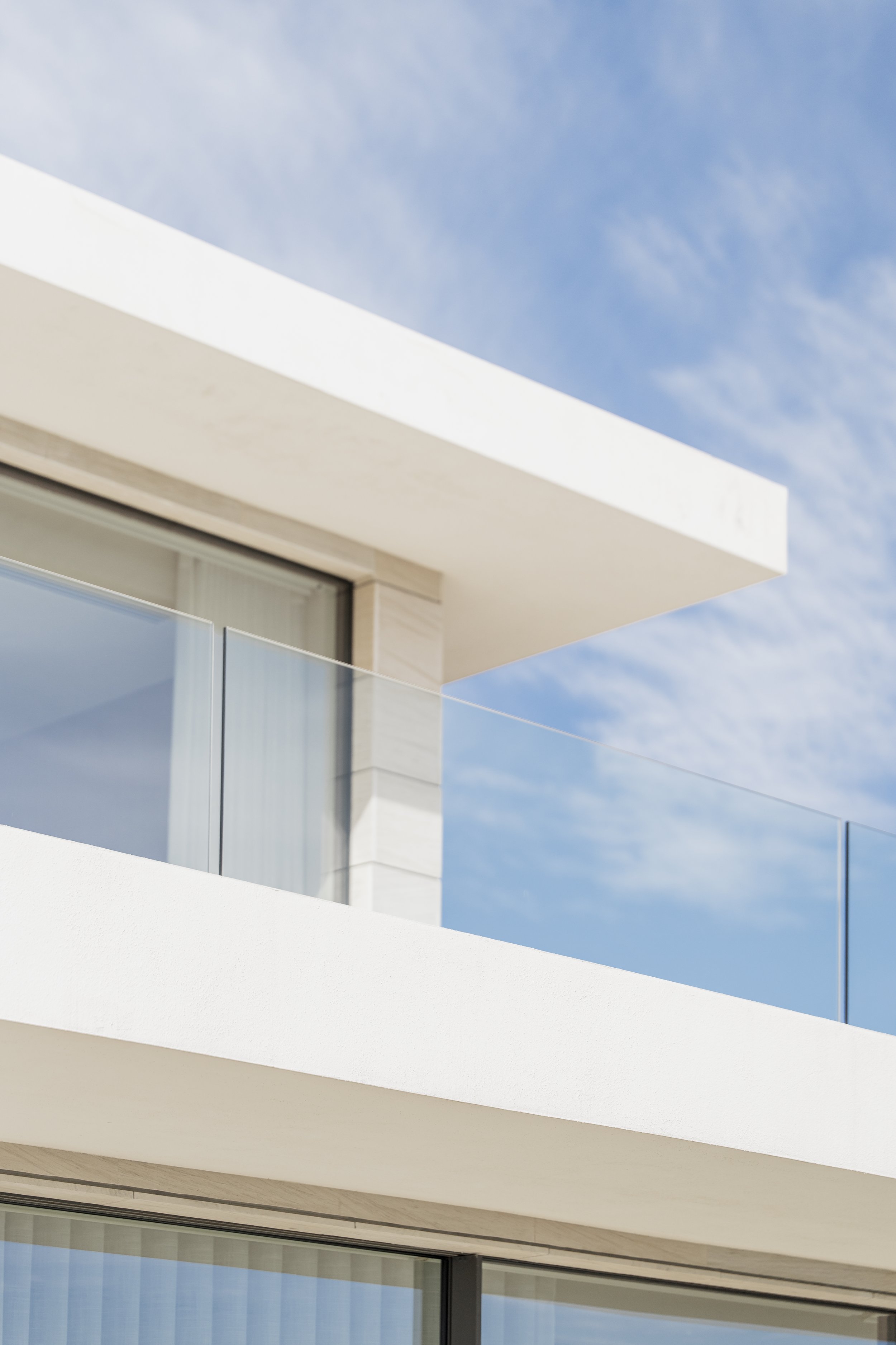 Sala de estar moderna con sofá blanco, cojines decorativos, mesa de centro con libros, comedor al fondo, ventanas grandes, y decoración elegante.