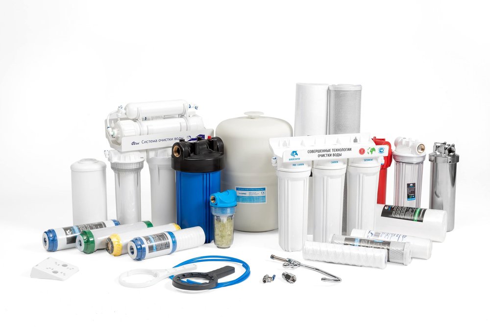 Reverse osmosis system parts, filter cartridges, membranes, and fittings laid out on a white table