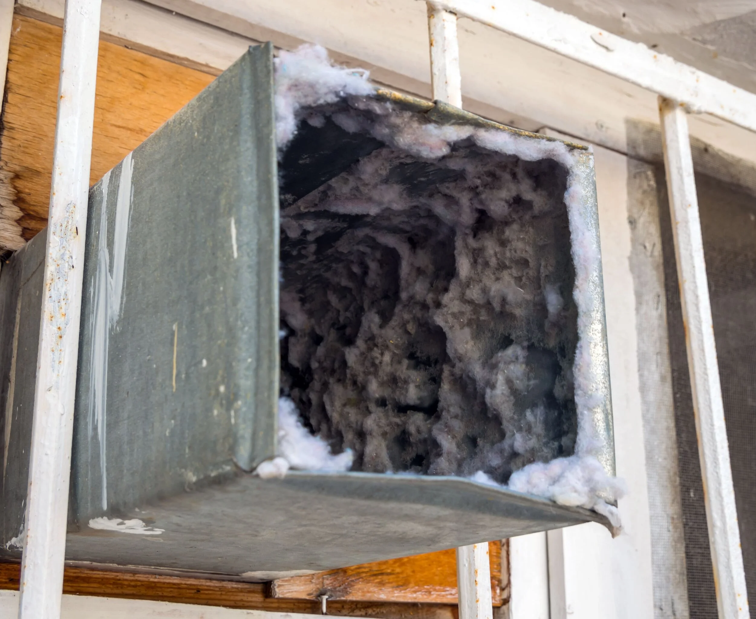 Interior of an air duct heavily coated with dust before cleaning.