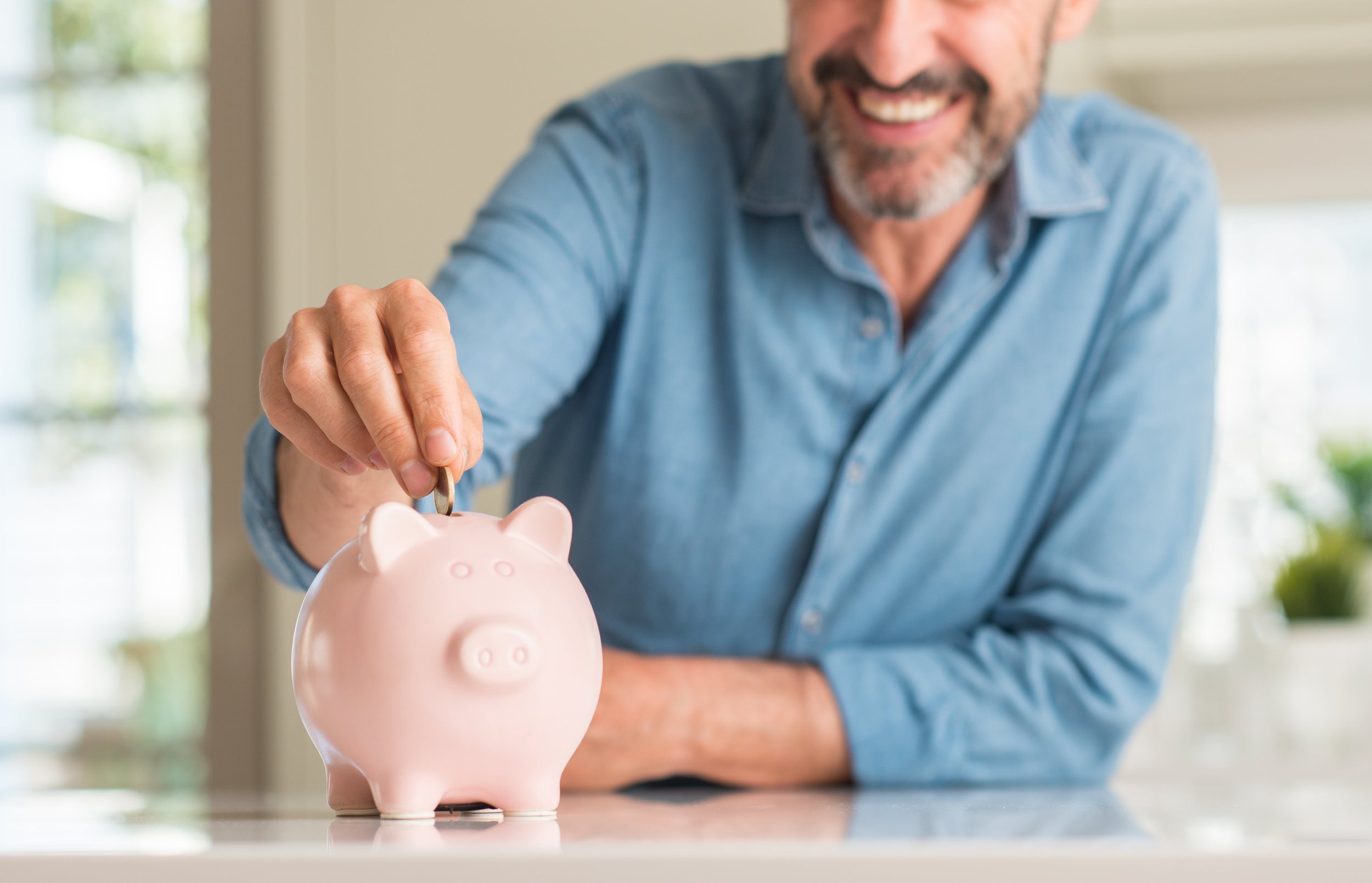 smiling-man-adding-money-into-piggy-bank