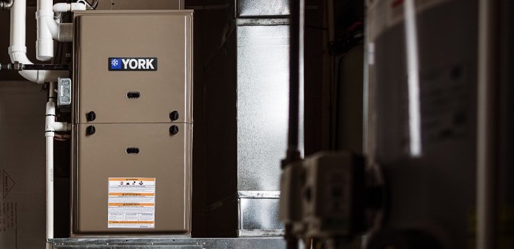 An installed York brand furnace located in basement beside ductwork