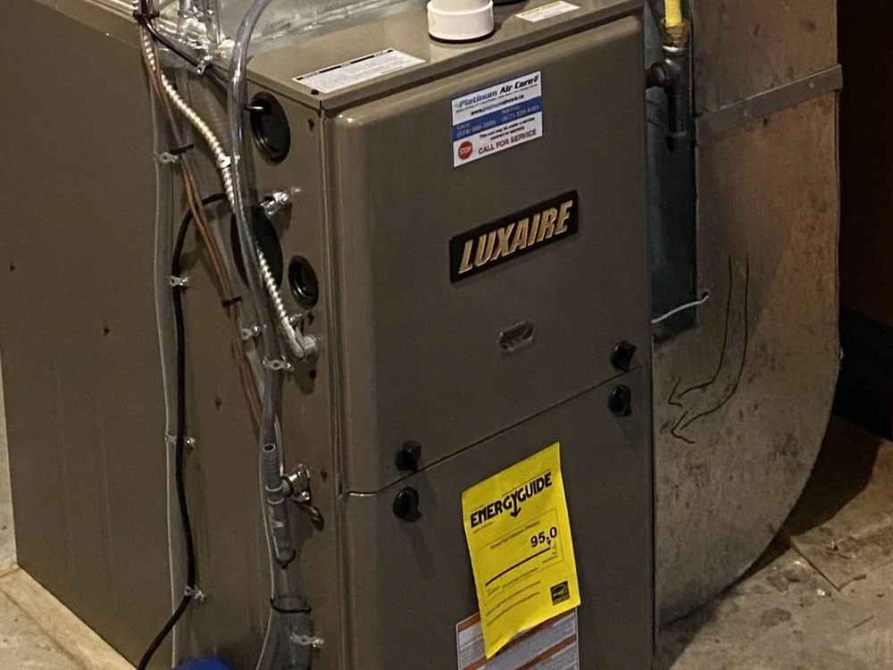 Luxaire high-efficiency gas furnace in a home basement, with a Platinum Air Care service sticker on the cabinet