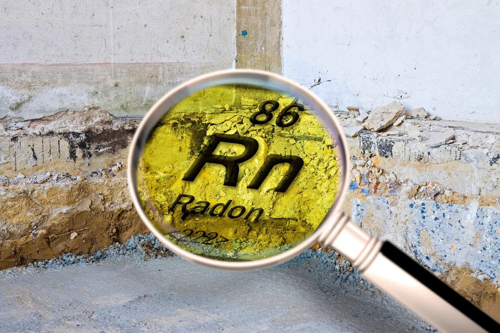 Magnifying glass over the chemical symbol Rn for radon, element 86, in front of a basement foundation wall