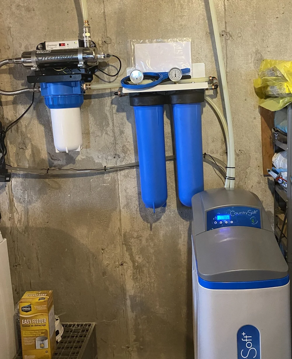 A UV water disinfection system, filter housings, and a CountrySoft water conditioner installed on a basement wall