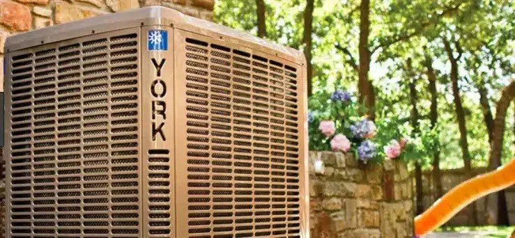 A York central air conditioner, the outdoor unit beside a stone wall