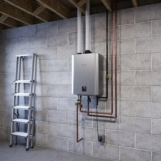 Rinnai SENSEI RX tankless water heater mounted on a concrete block basement wall, with its gas and water lines