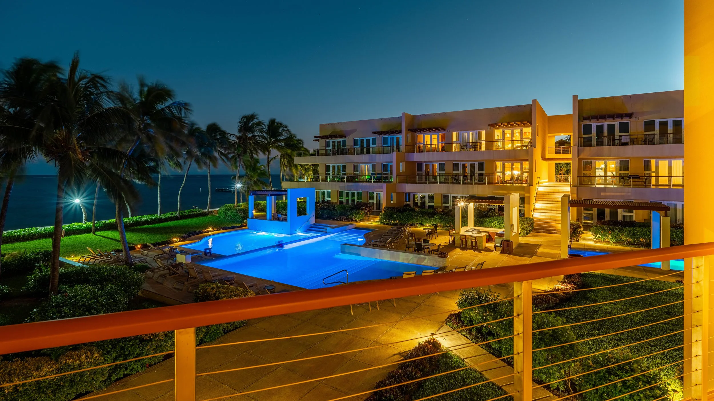 Aerial nighttime view of the illuminated infinity pools and luxury suites at The Phoenix Resort in San Pedro, Belize, overlooking the Caribbean Sea.