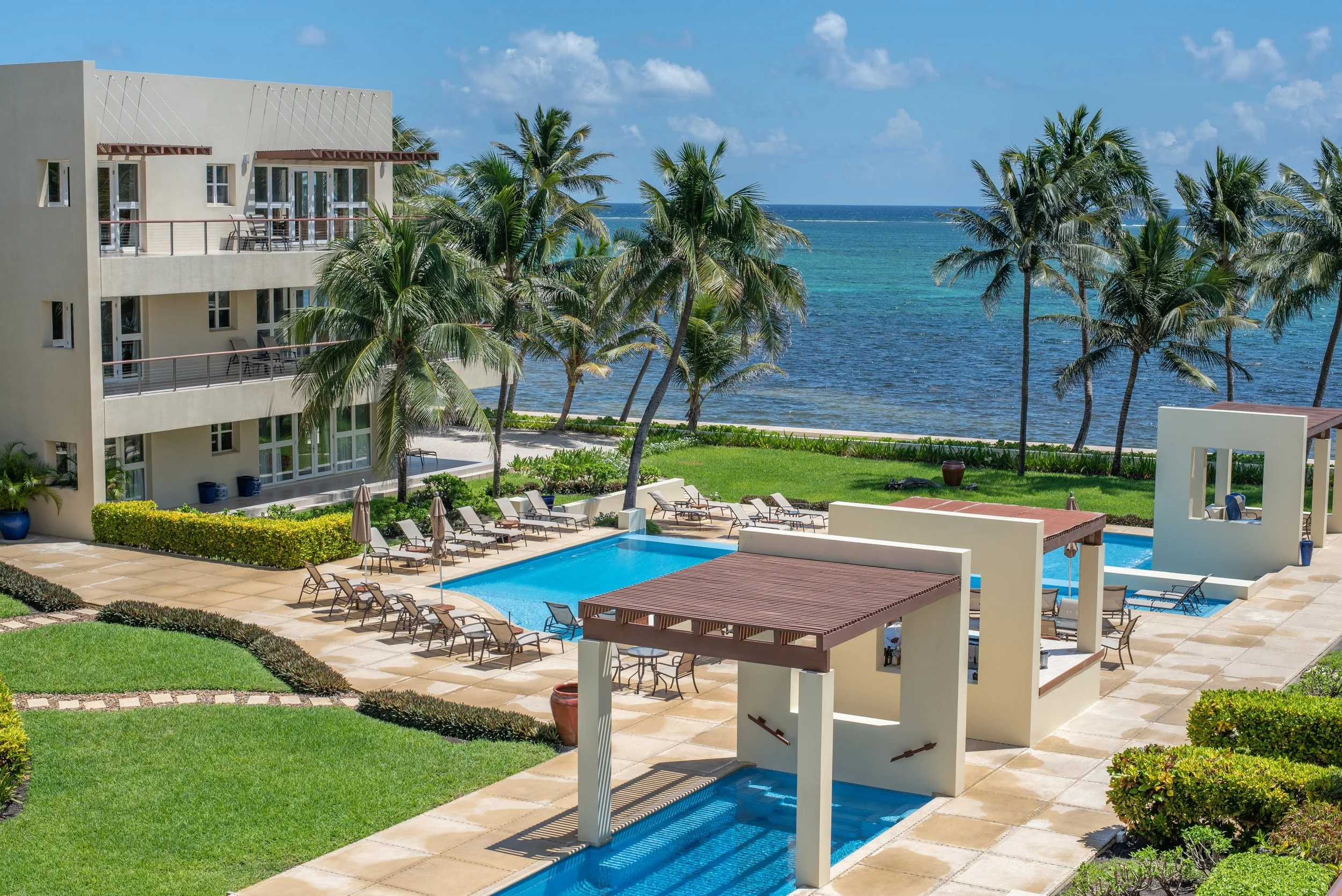 Elevated view of luxury oceanfront condo suites swimming pools manicured lawns and palm trees overlooking the Caribbean Sea at The Phoenix Resort in San Pedro Belize.