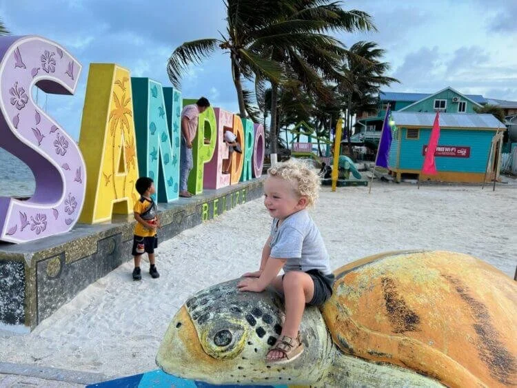 Two children playing at the colorful San Pedro Town sign in Central Park, a short walk from The Phoenix Resort in San Pedro, Belize.