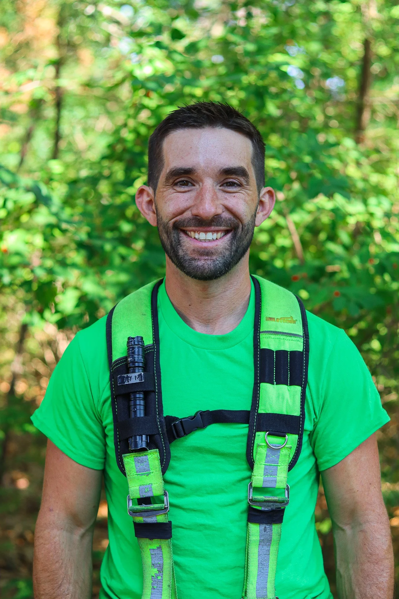 Smiling arborist wearing safety gear in forest
