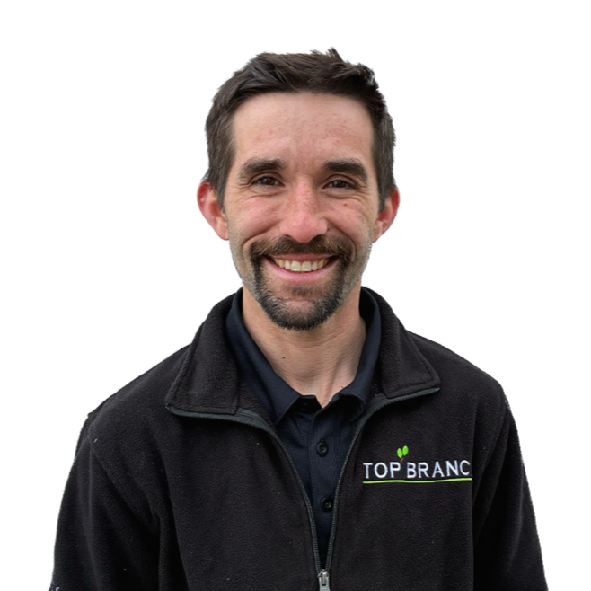 Casey Elmer, maine arborist wearing a black jacket with a 'Top Branch' logo.