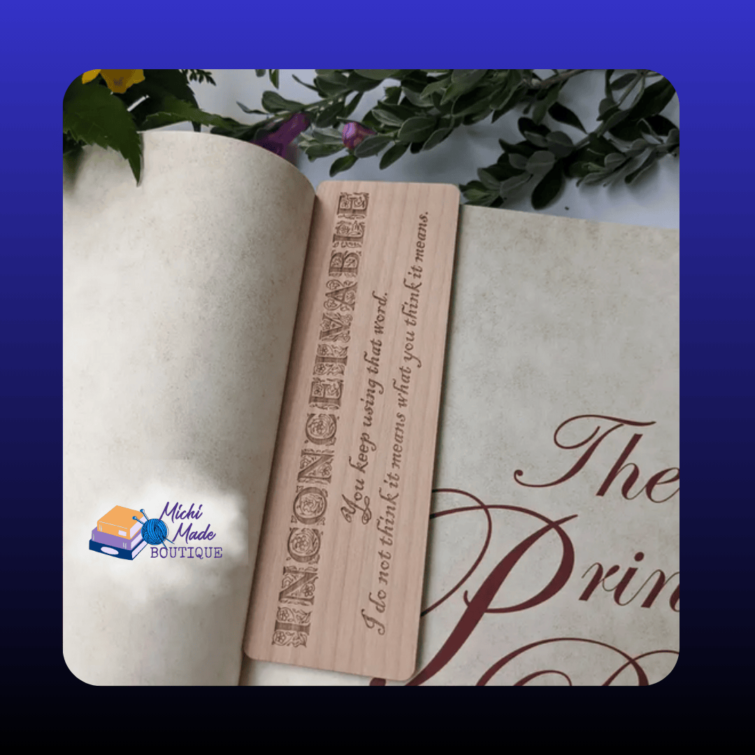 In-book view: “Alder wood bookmark engraved with ‘Inconceivable’ and the quote, resting inside an open book among greenery.”