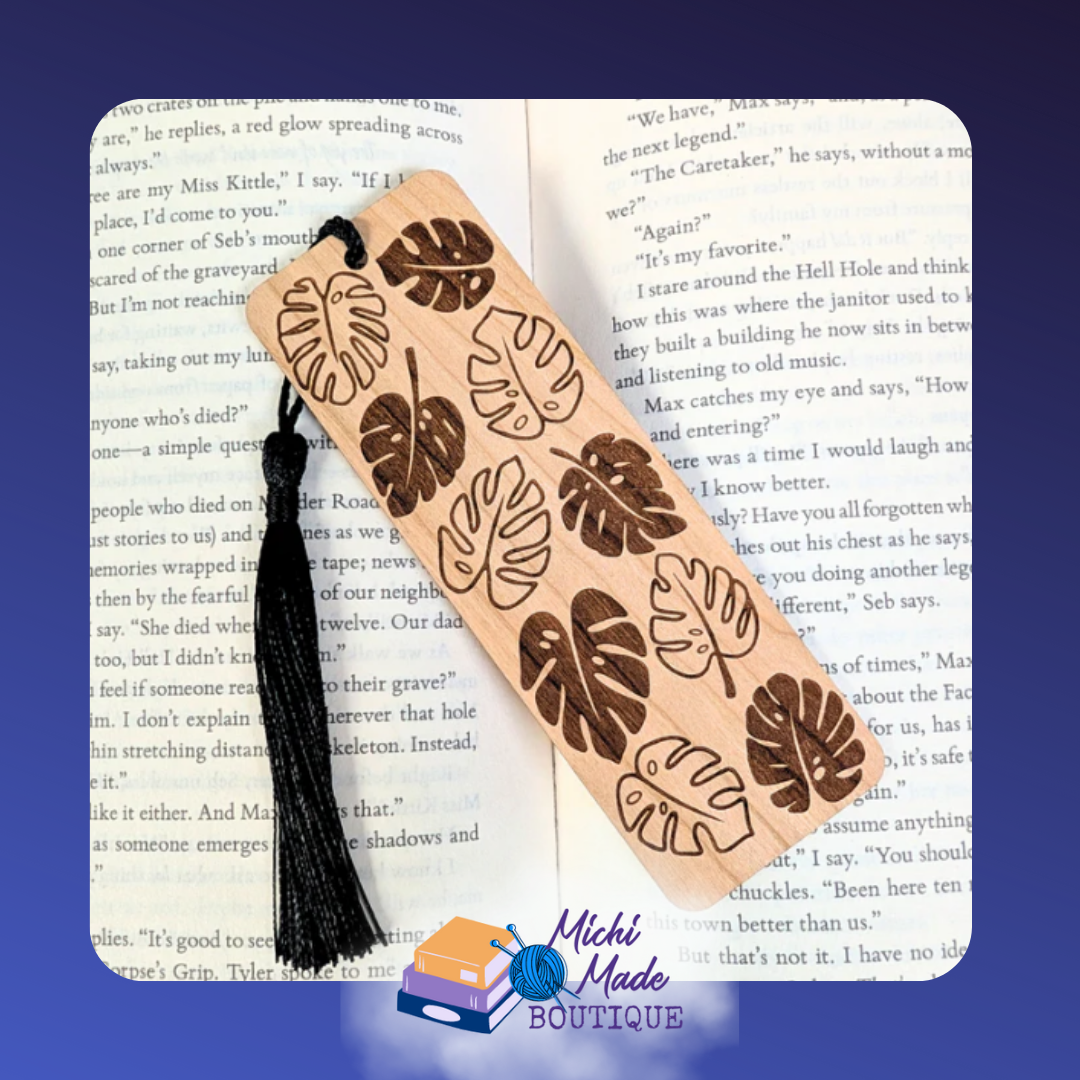 Wooden bookmark with engraved monstera leaves pattern, black tassel attached.