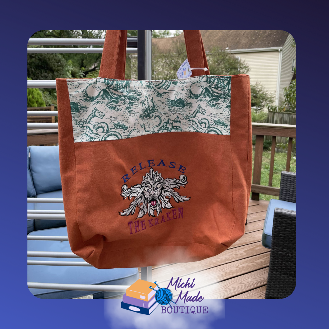 Release the Kraken Embroidered Tote Bag. Terracotta orange tote bag with a vintage sea monster fabric panel & Release the Kraken embroidered in navy text above a sea creature face.