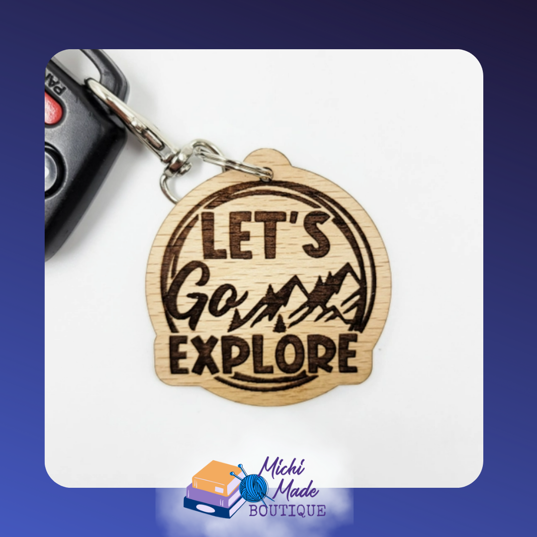Round wood keychain with “Let’s Go Explore” and mountain silhouette inside.