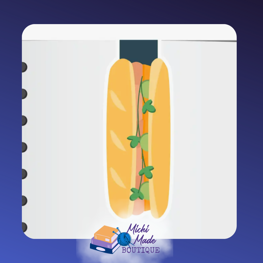 A smiling sub sandwich bookmark layered with veggies and herbs, clipped on a planner page.