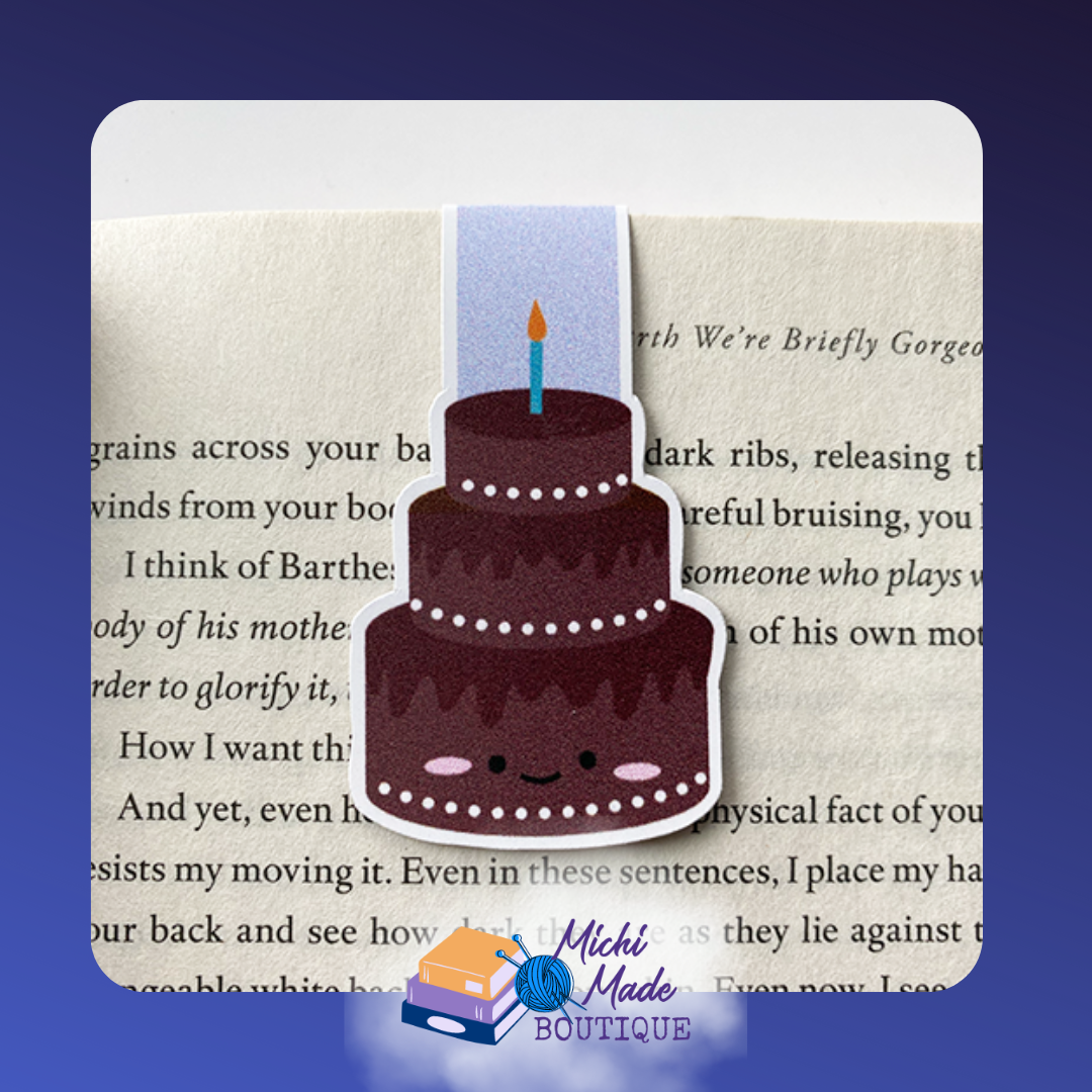 Chocolate cake magnetic bookmark with three tiers, smiling face, and a single lit candle on top.