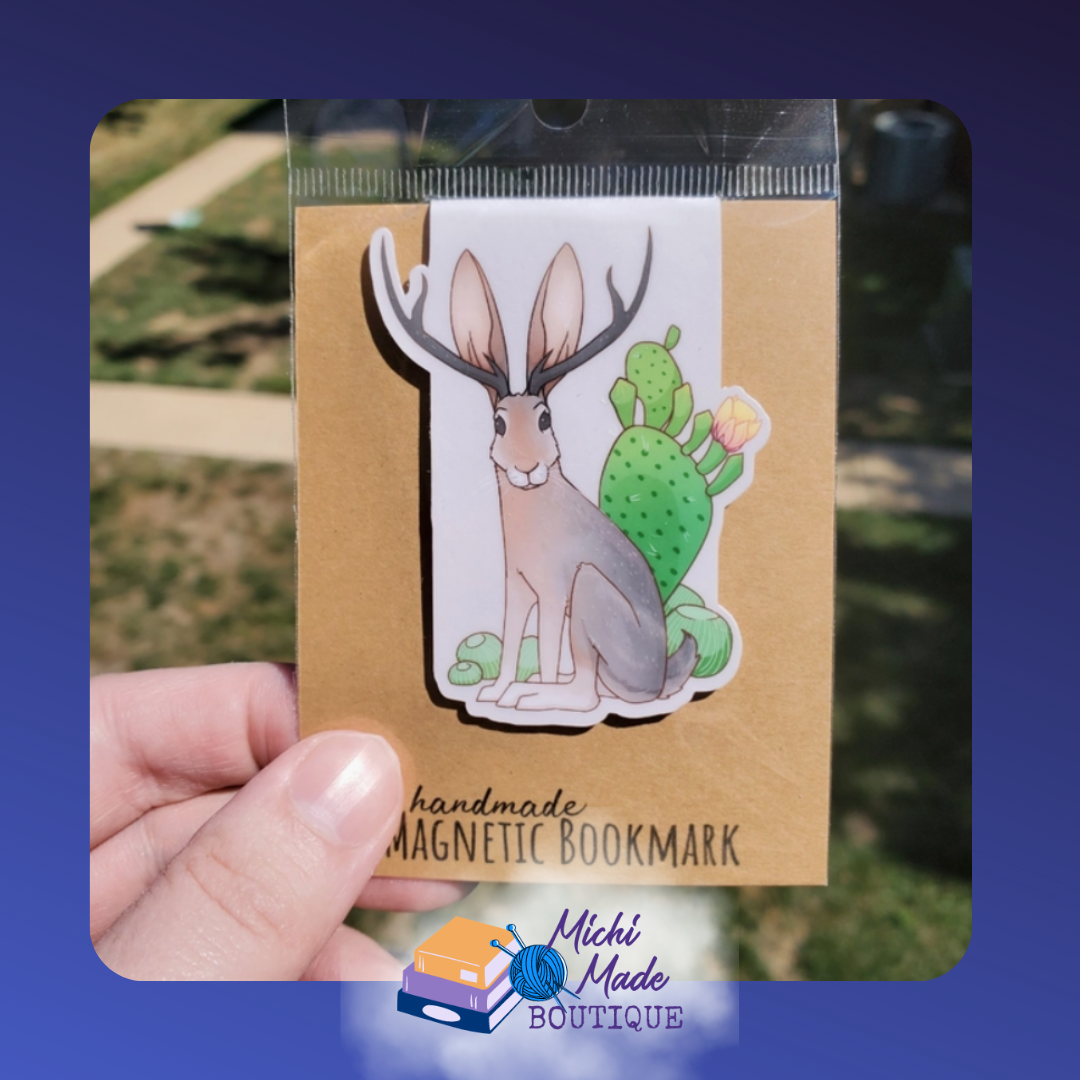 Cute jackalope with big antlers and a fluffy tail in front of a cactus.