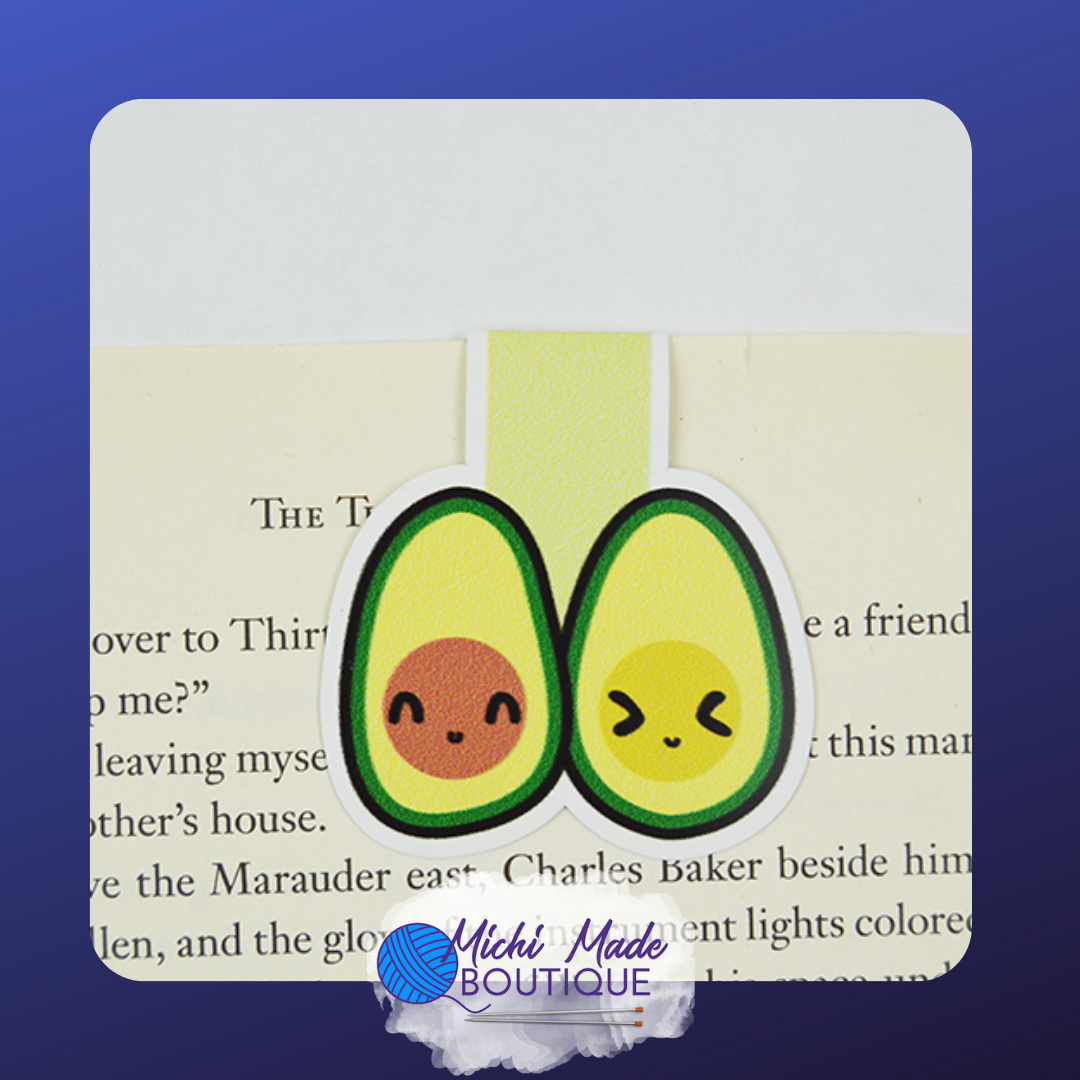 Cute avocado pair magnetic bookmark with smiling faces, clipped onto a book page.