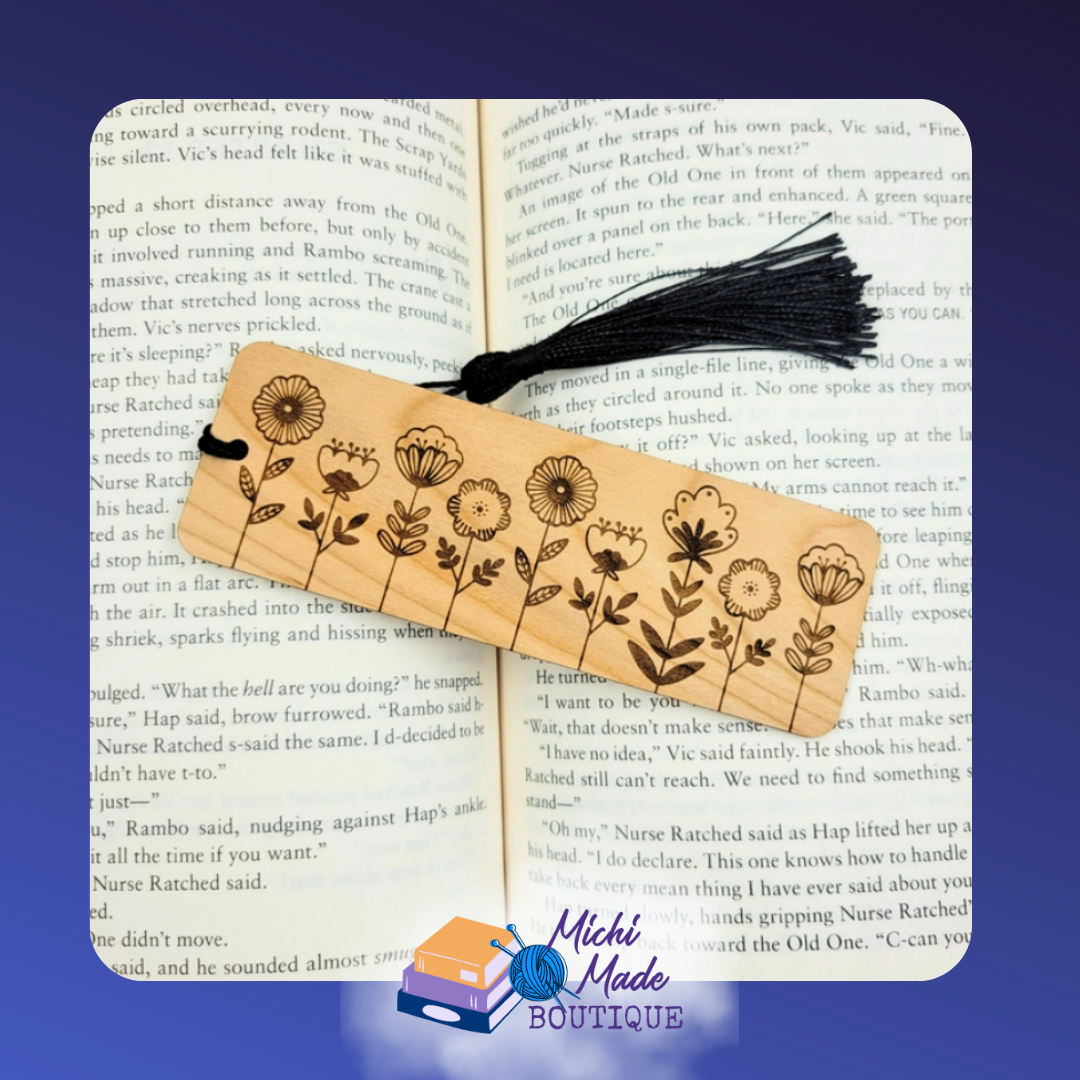 Wooden bookmark with engraved folk art flowers and black tassel, resting inside an open book.