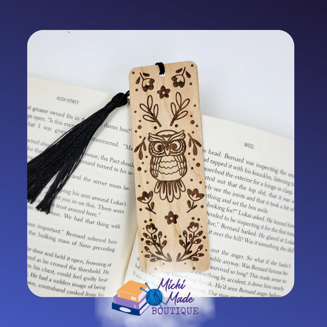 Wooden bookmark with engraved folk art owl and floral accents, black tassel, on open book.