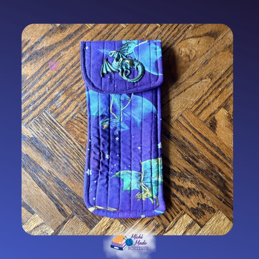 Dragon Flight Deep Purple. Quilted eyeglass case in deep purple with flying dragon silhouettes in teal, blue, and green with scattered stars, fastened by a bronze winged dragon decorative button.