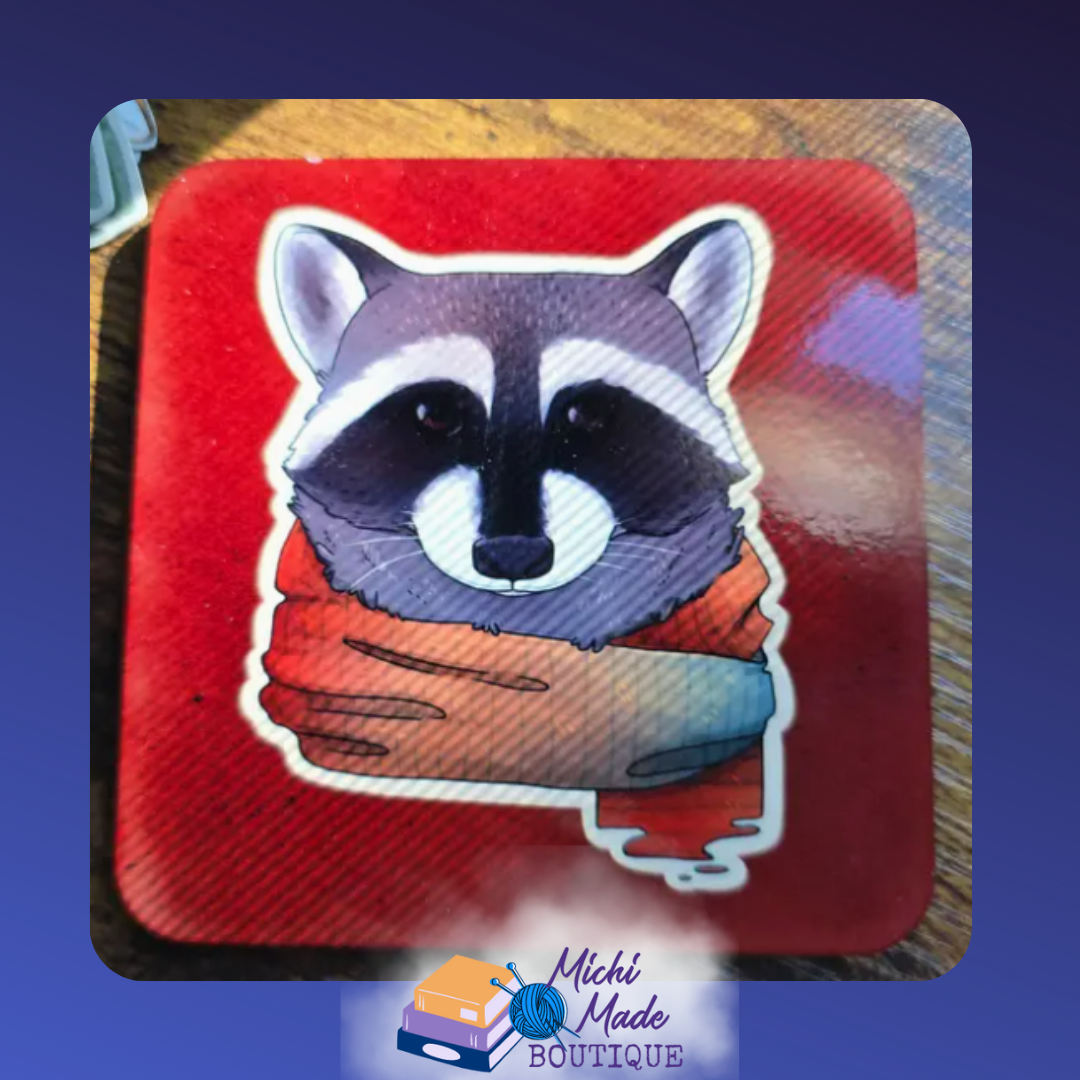 Illustrated coaster of a raccoon in an orange scarf on a red background.