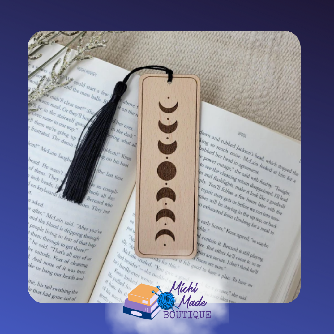 Wooden bookmark with engraved moon phases design, black tassel attached.