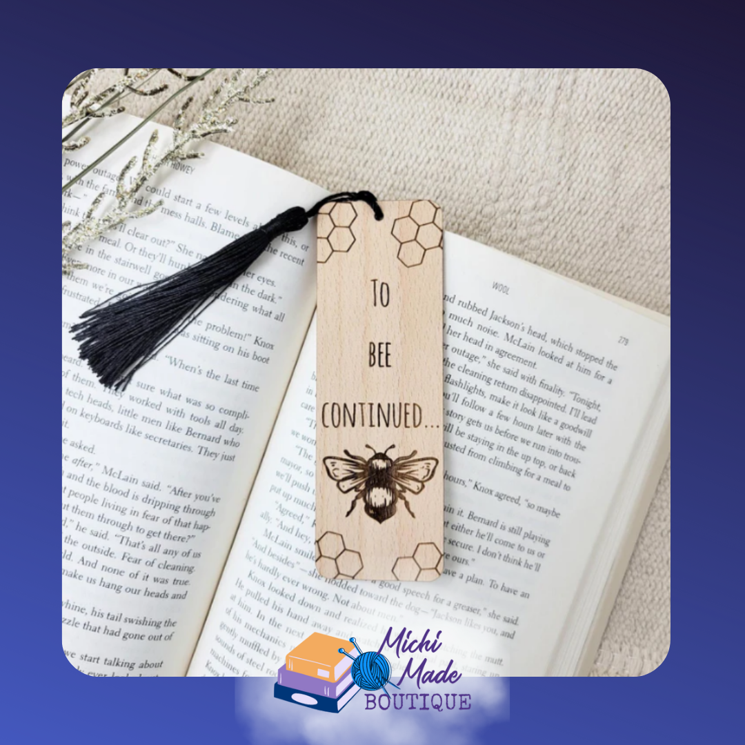 Wooden bookmark with “To Bee Continued” text, honeycomb accents, engraved bee, and black tassel attached.