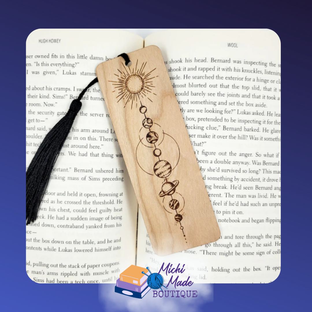 Wooden bookmark with engraved solar system and sun design, black tassel attached.