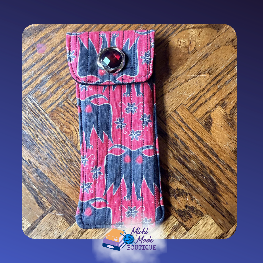 Mothman Case.png Quilted eyeglass case in red with black Mothman silhouette print and glowing red eyes, decorated with a round red gem button.