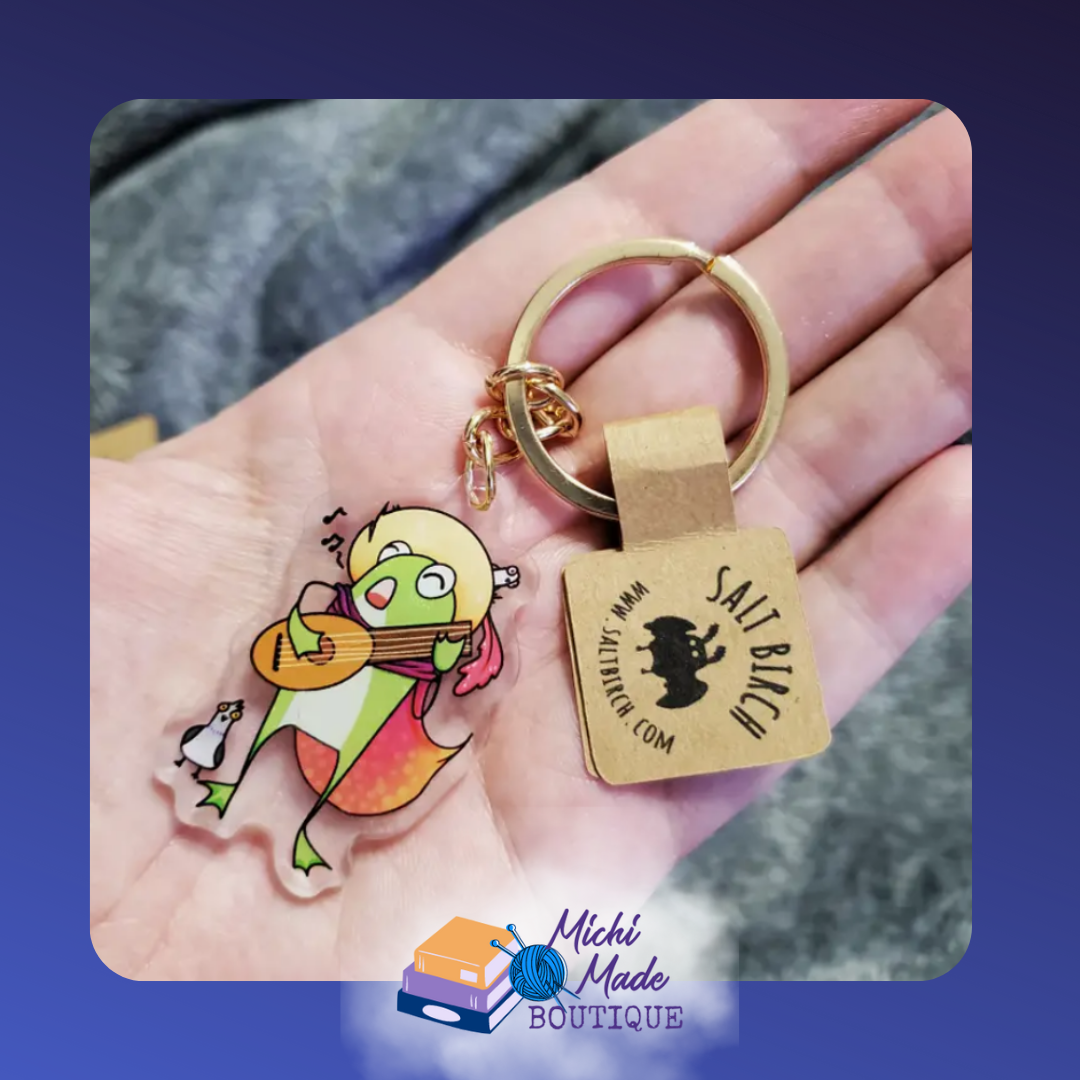 Bard frog keychain strumming lute with penguin companion.