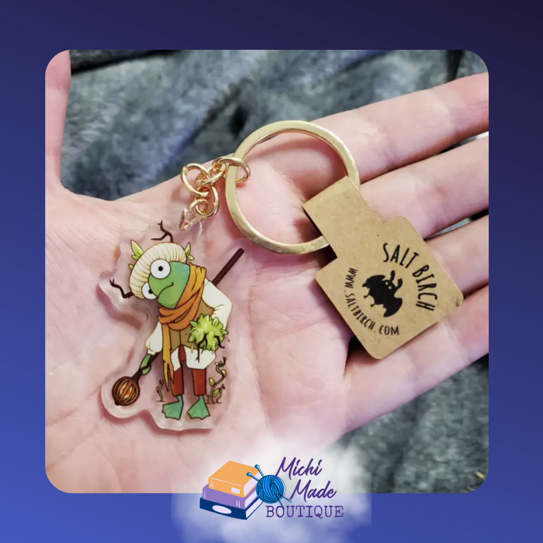 Druid frog keychain in scarf holding leafy staff.