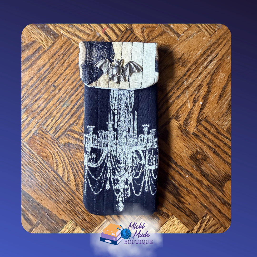 Gothic Chandlier Case.png Quilted eyeglass case in black with a large white chandelier illustration, two-tone cream and black flap, and silver bat button.