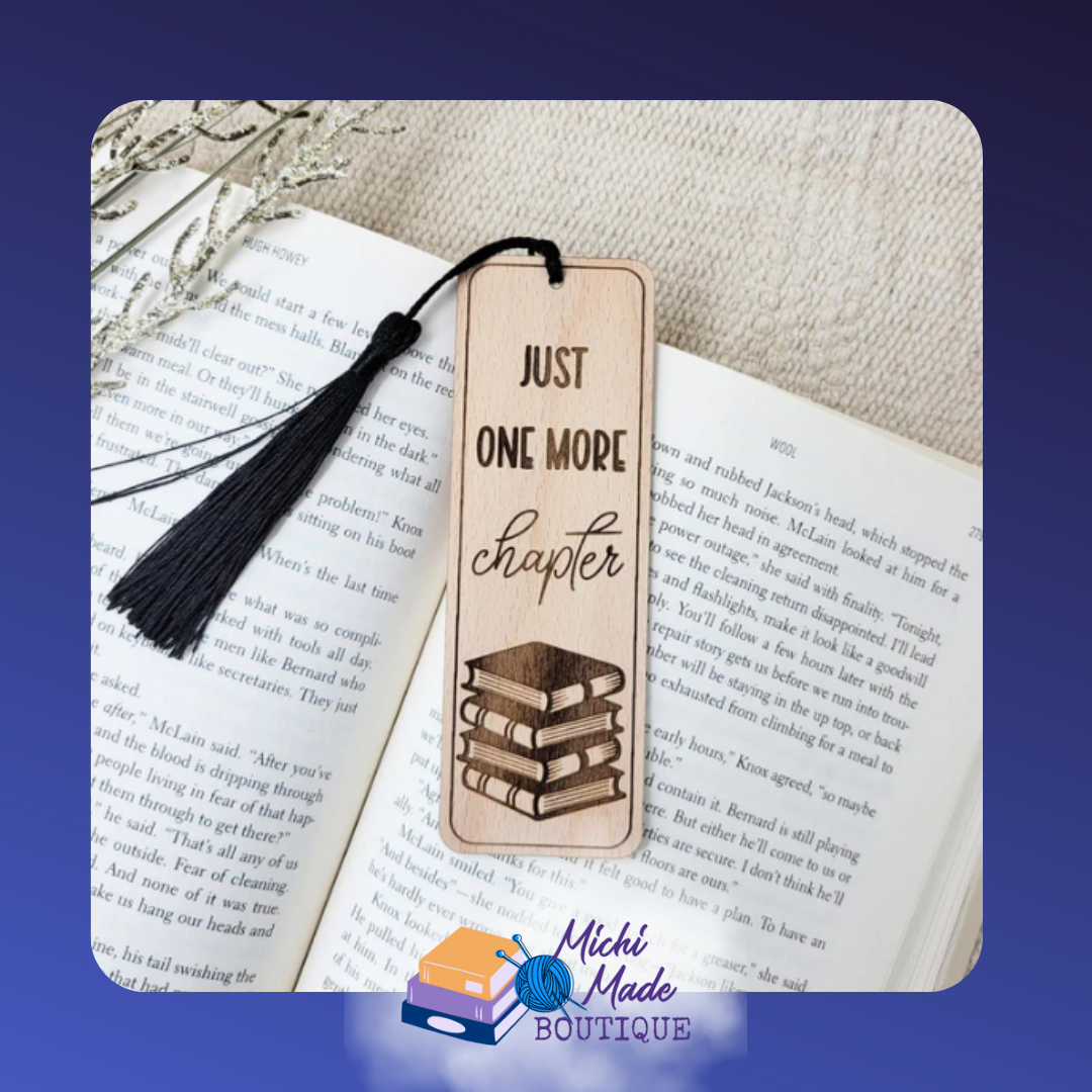 Wooden bookmark with “Just One More Chapter” text and stacked books design, black tassel attached.