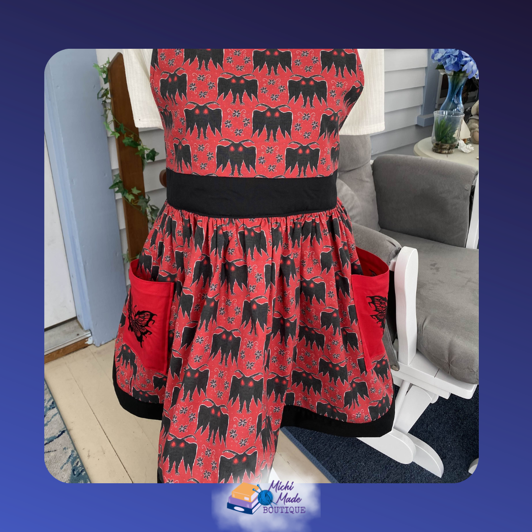Mothman_2.png Full gathered red apron skirt with two large red patch pockets each featuring an embroidered black skull moth, finished with a black hem band.