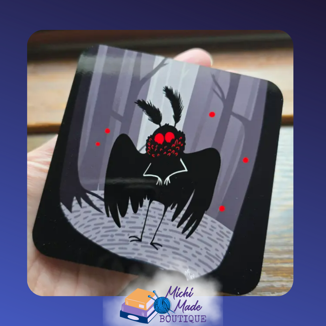 Illustrated coaster of a black Mothman with glowing red eyes standing in a dark, eerie forest.