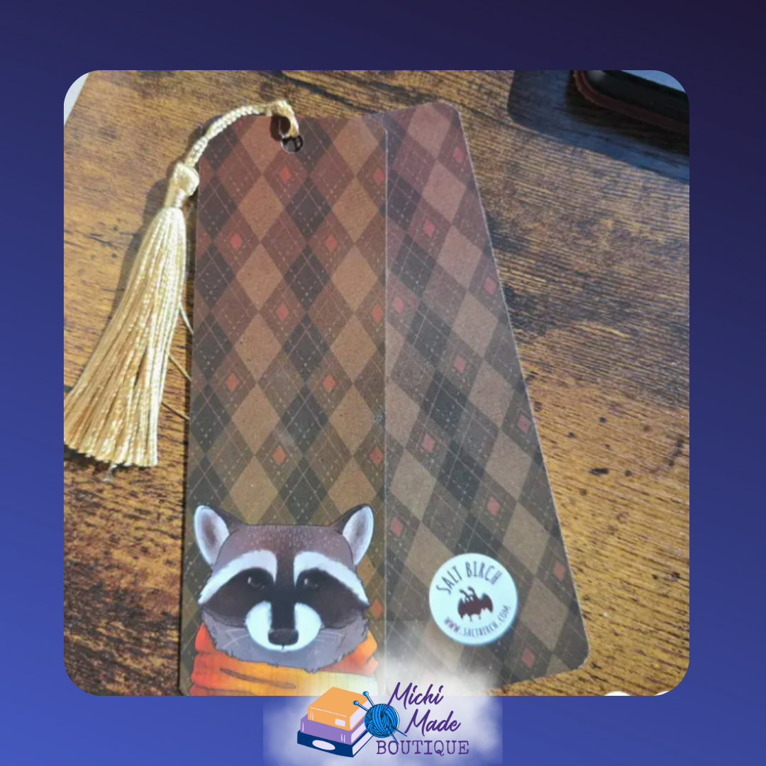 2"x6" bookmark with raccoon in scarf on brown argyle background, gold tassel attached.